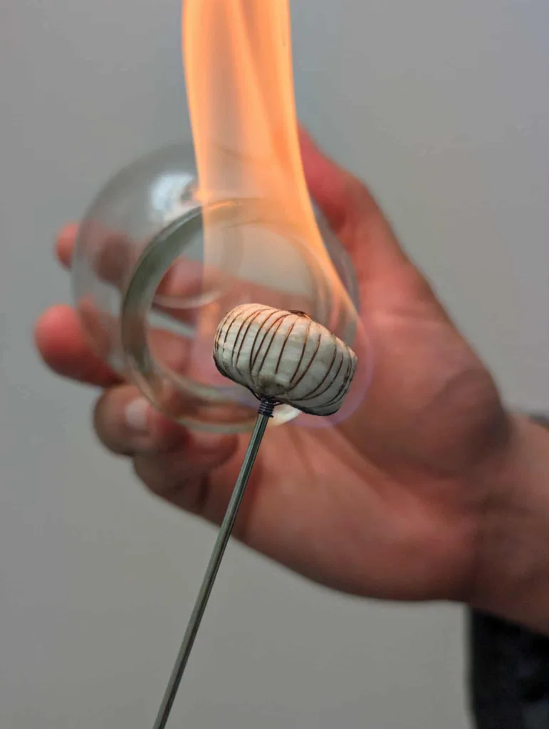 Hand performing fire cupping therapy with flame inside glass cup