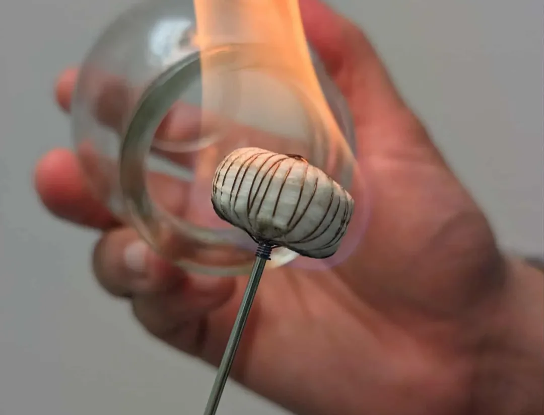 Hand performing fire cupping therapy with flame inside glass cup